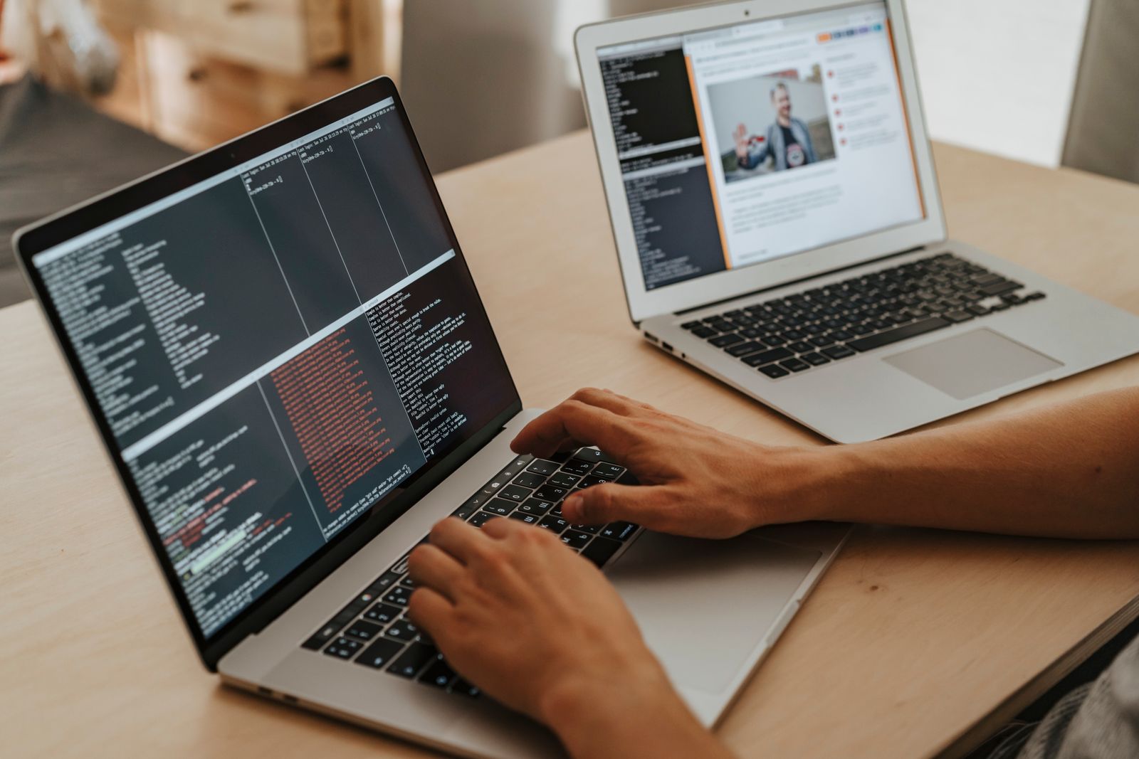 Personas trabajando en dos computadores sobre una mesa de madera